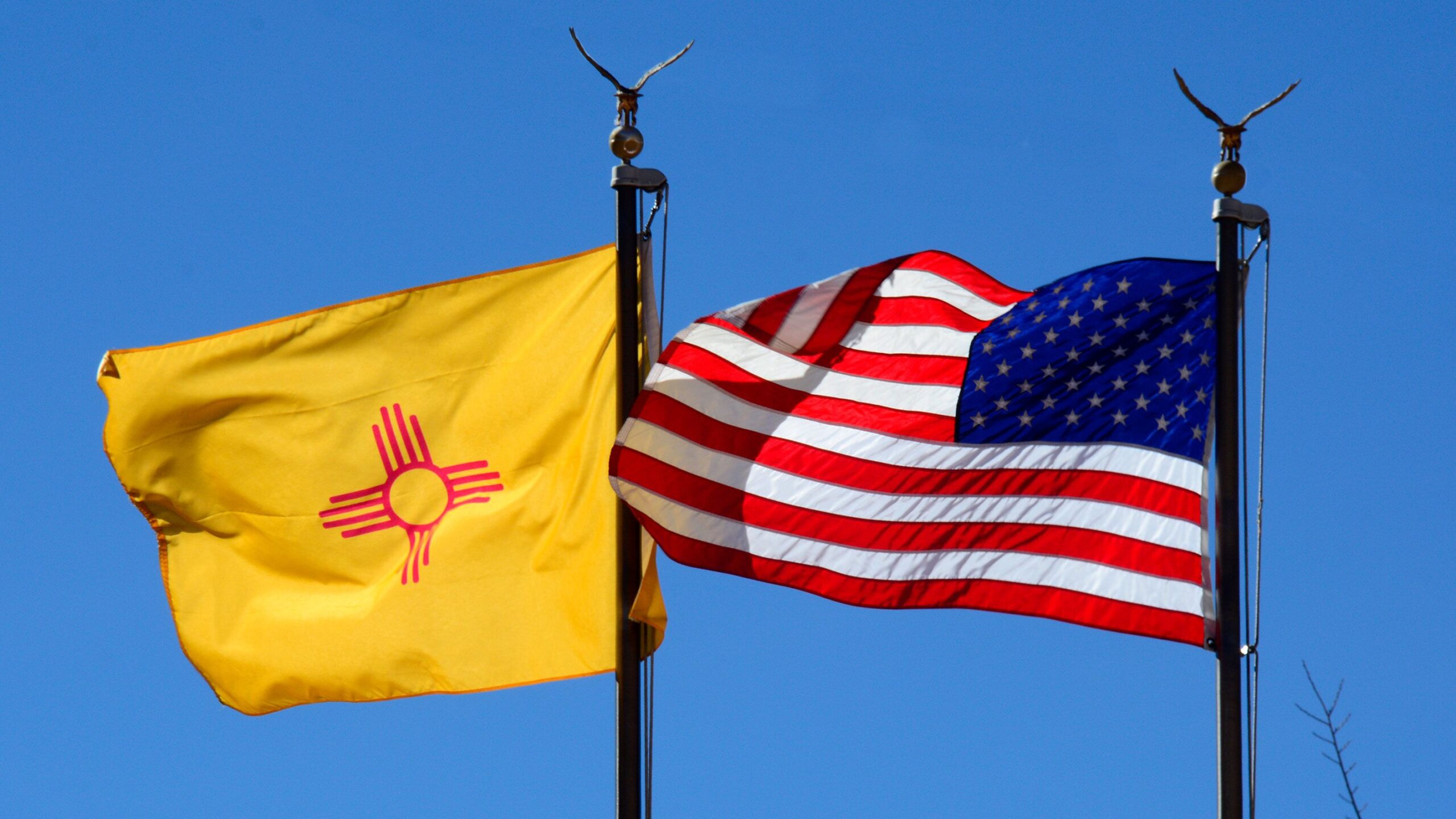 The New Mexico state flag and the American flag fly side-by-side in Santa Fe