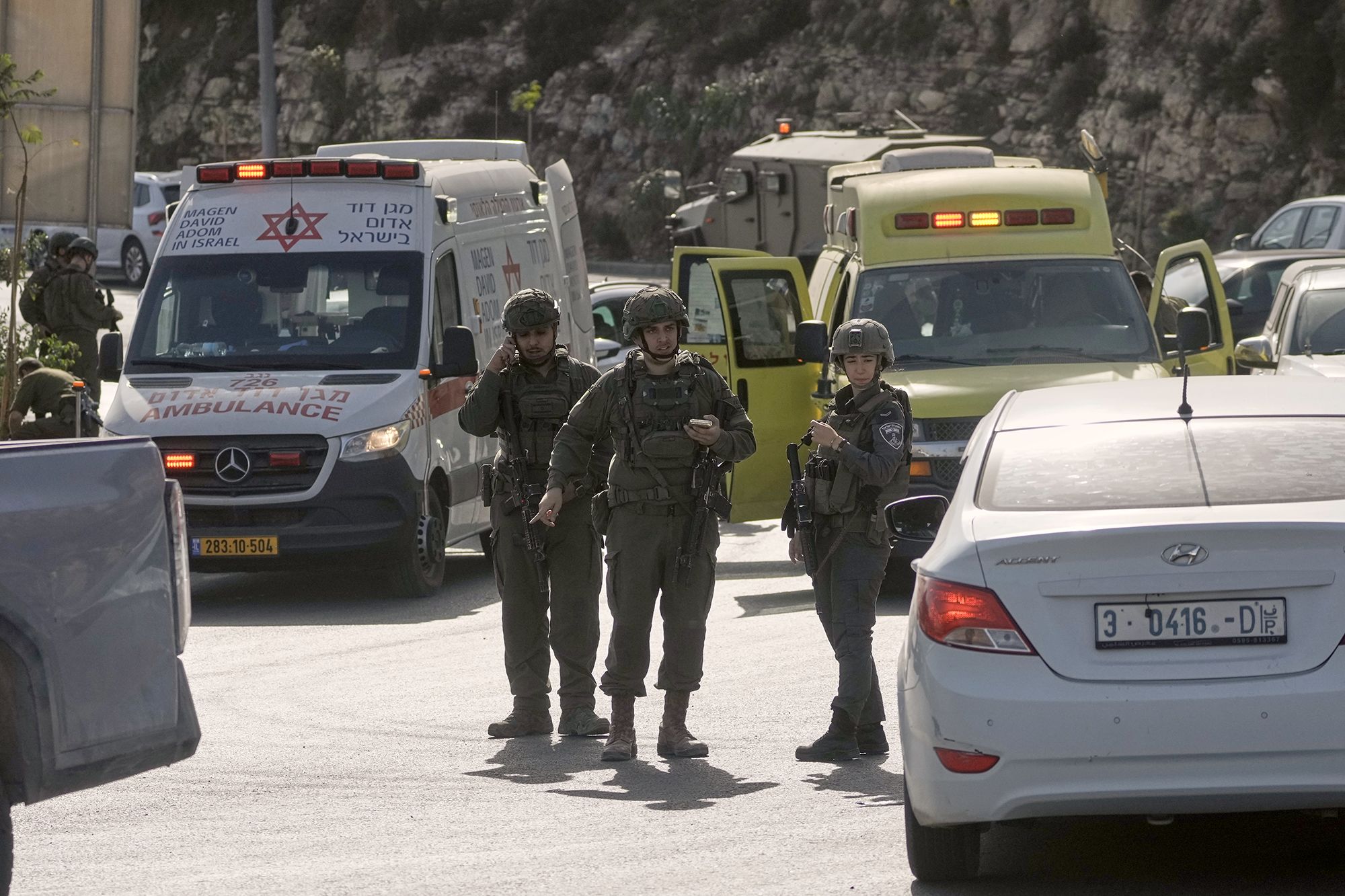 Israeli soldiers and emergency personnel gather near the scene of a shooting attack at a junction near Hebron in the occupied West Bank