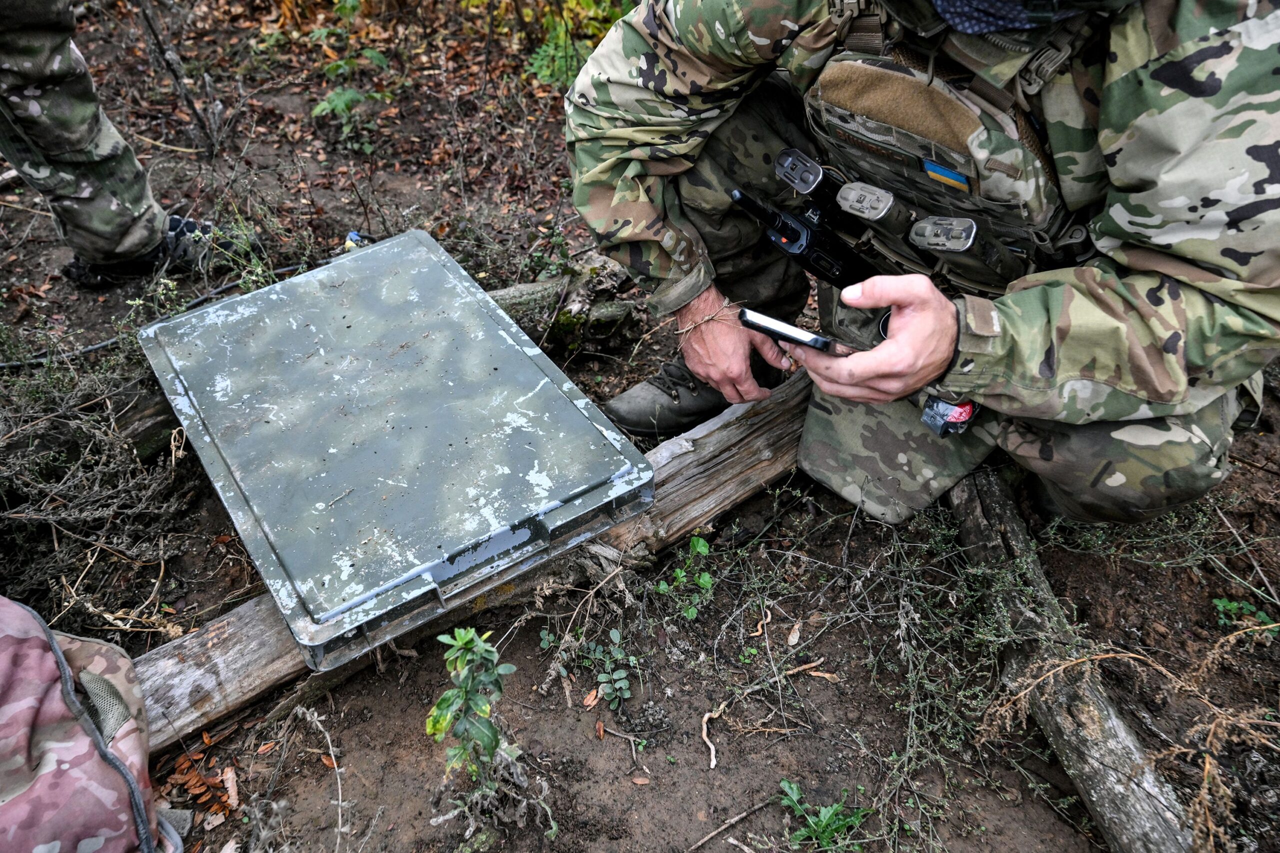 A soldier uses a smartphone to check signal quality while setting up a Starlink satellite communication network in the Donetsk region
